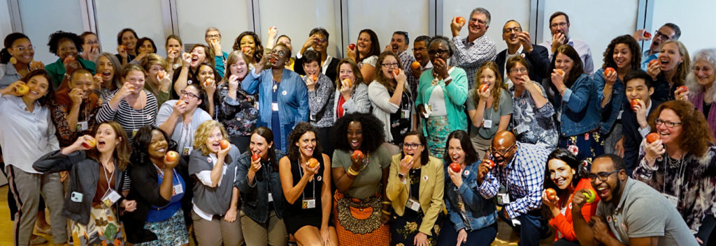 Group Of People Smiling, Biting Into Apples